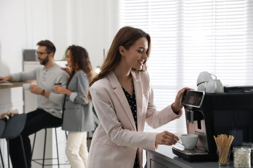 Chica haciendo una cafe en la cocina de la oficina